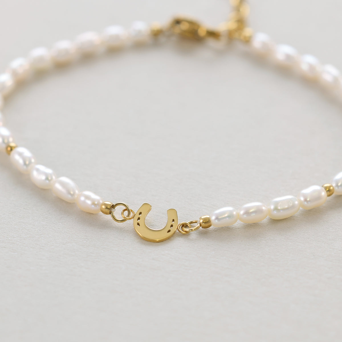 Perlenarmband mit goldenem Hufeisen-Anhänger, Nahaufnahme des Verschlussbereichs