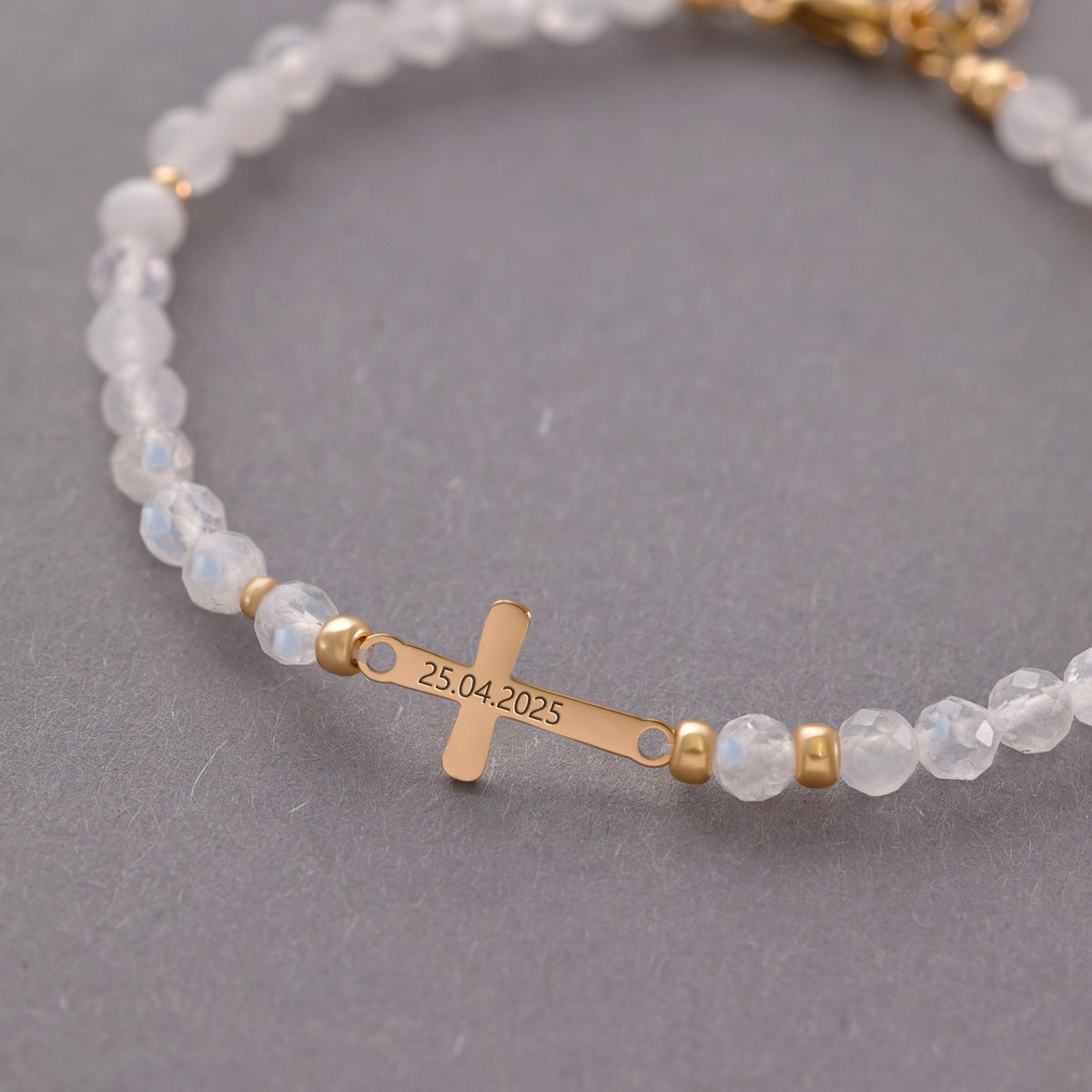 Nahaufnahme Mondstein Kreuz-Armband mit graviertem Datum 25.04.2025 auf dem Kreuz