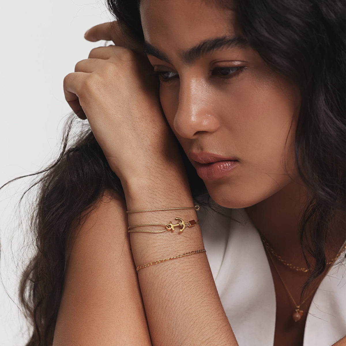 Frau trägt goldenes Unisex Armband mit Gravur & Ankerhaken, Hand ruht am Kopf