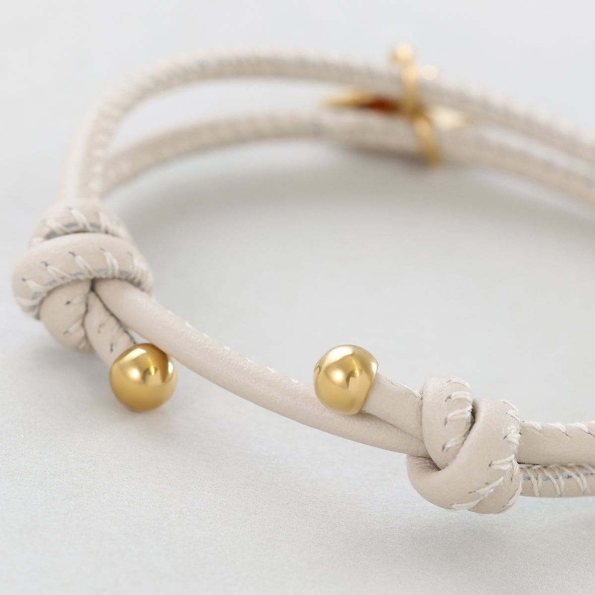 Personalisiertes Lederarmband mit Gravurplättchen in Beige – Nahaufnahme des Knotens mit goldenen Kugelverschlüssen