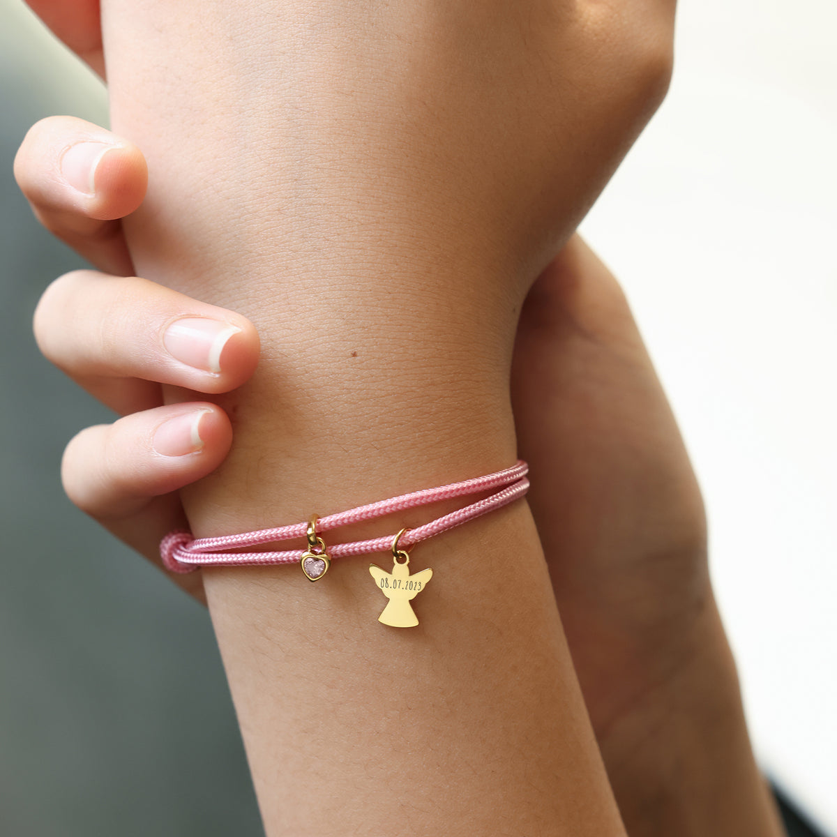 Kind trägt personalisiertes Segeltau Armband mit goldenem Schutzengel und graviertem Datum am Handgelenk