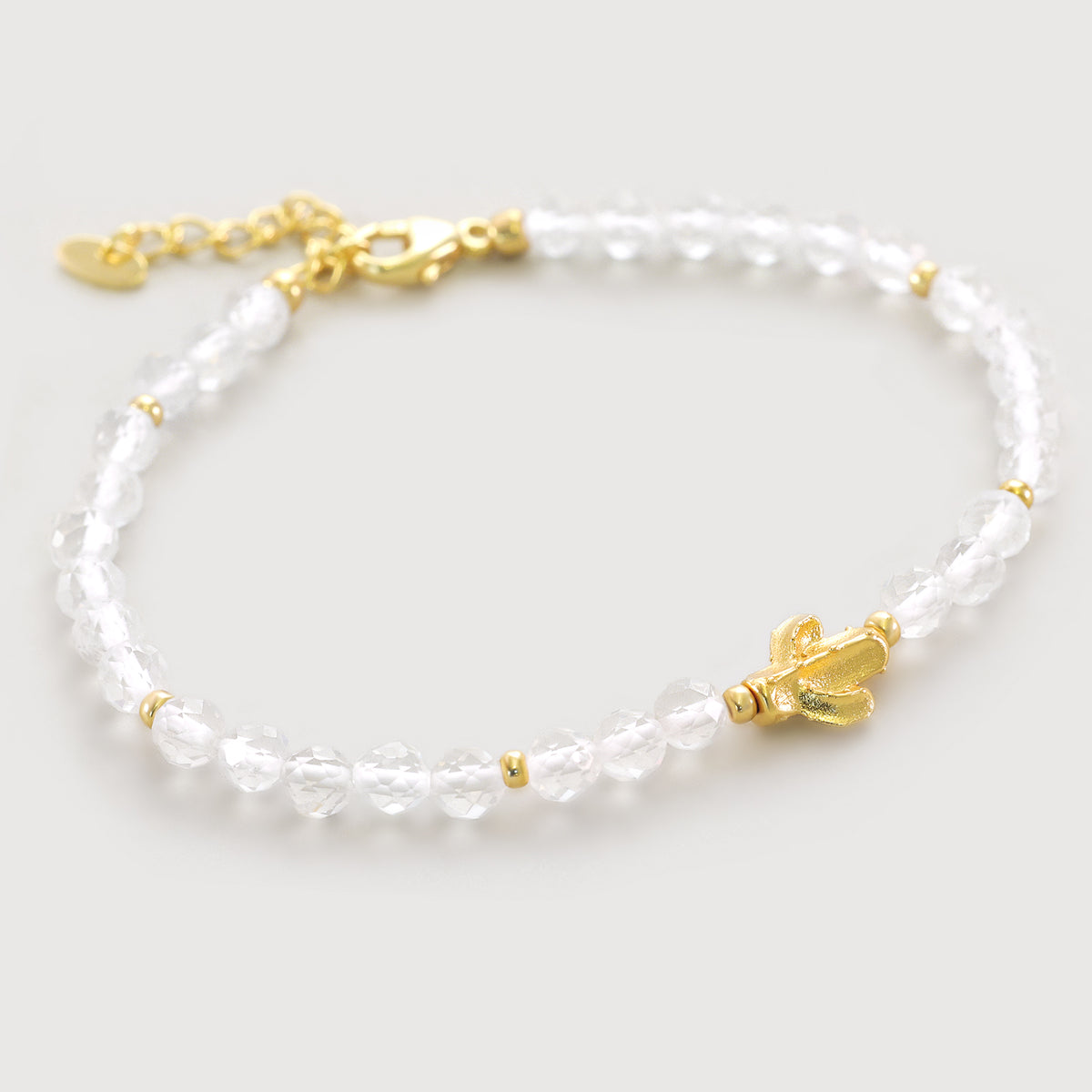 Bergkristall Armband mit goldenem Kaktus-Anhänger, freigestellt auf hellem Hintergrund