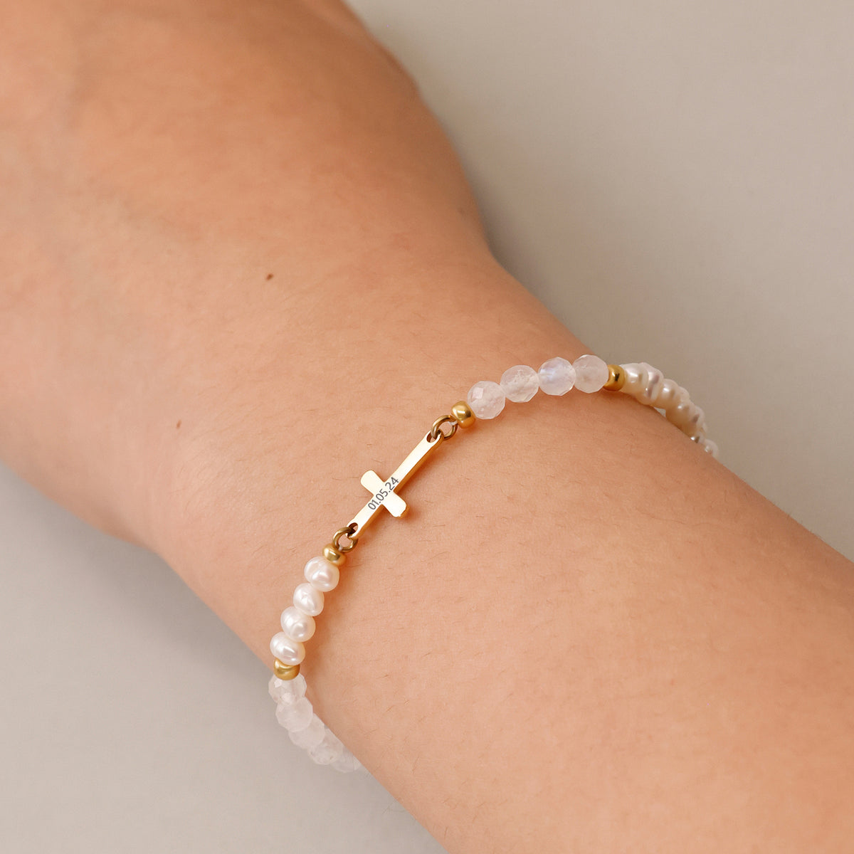 Frau trägt Mondstein & Süßwasserperlen-Armband mit Kreuz zur Kommunion am Handgelenk