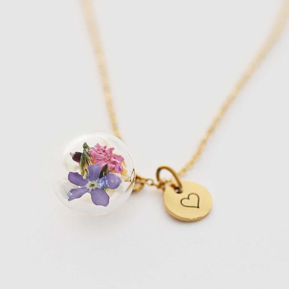 Kette mit echten Blüten in Glaskugel und goldenem Herz-Gravurplättchen, liegend