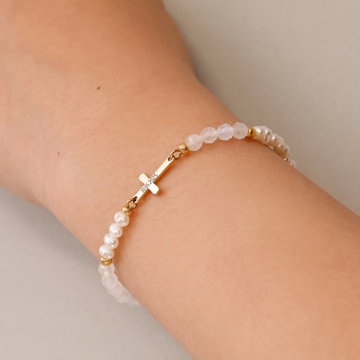 Frau trägt Mondstein & Süßwasserperlen-Armband mit Kreuz zur Konfirmation am Handgelenk
