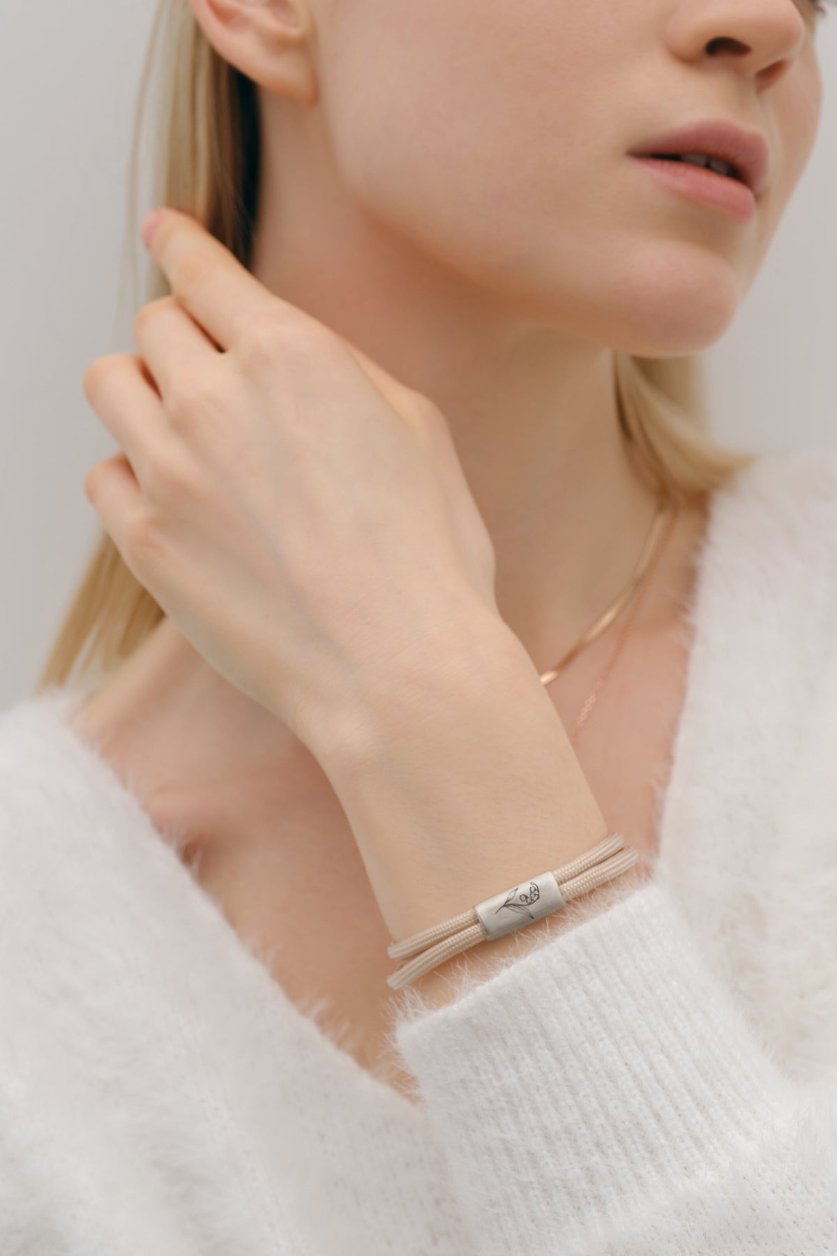 Geburtsblumen Armband aus Segeltau mit Wunschgravur in Beige – Frau trägt Armband, Hand am Nacken