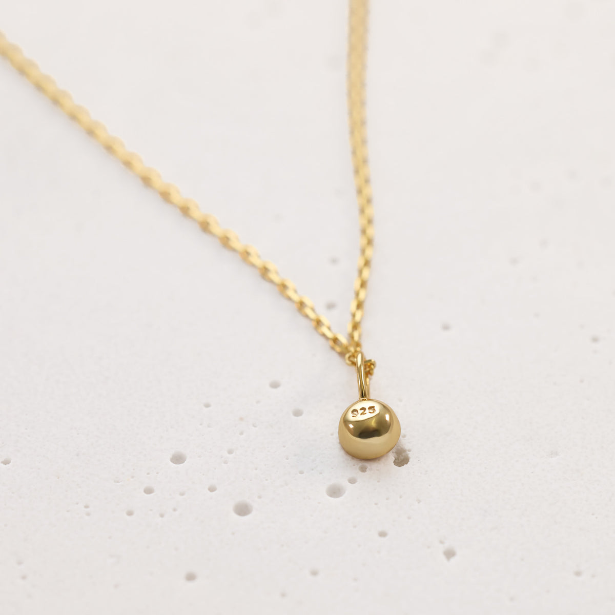 Nahaufnahme einer goldenen Anhänger-Kugel mit eingeprägtem 925er Silber-Stempel