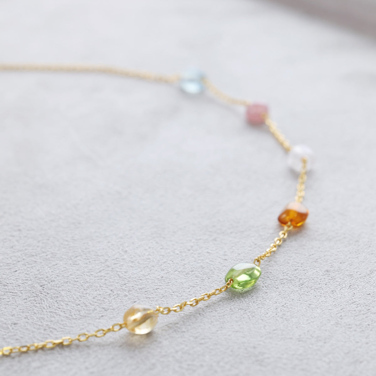 Nahaufnahme der Edelstein-Stationen an der Goldkette in Rosa, Weiß und Bernstein