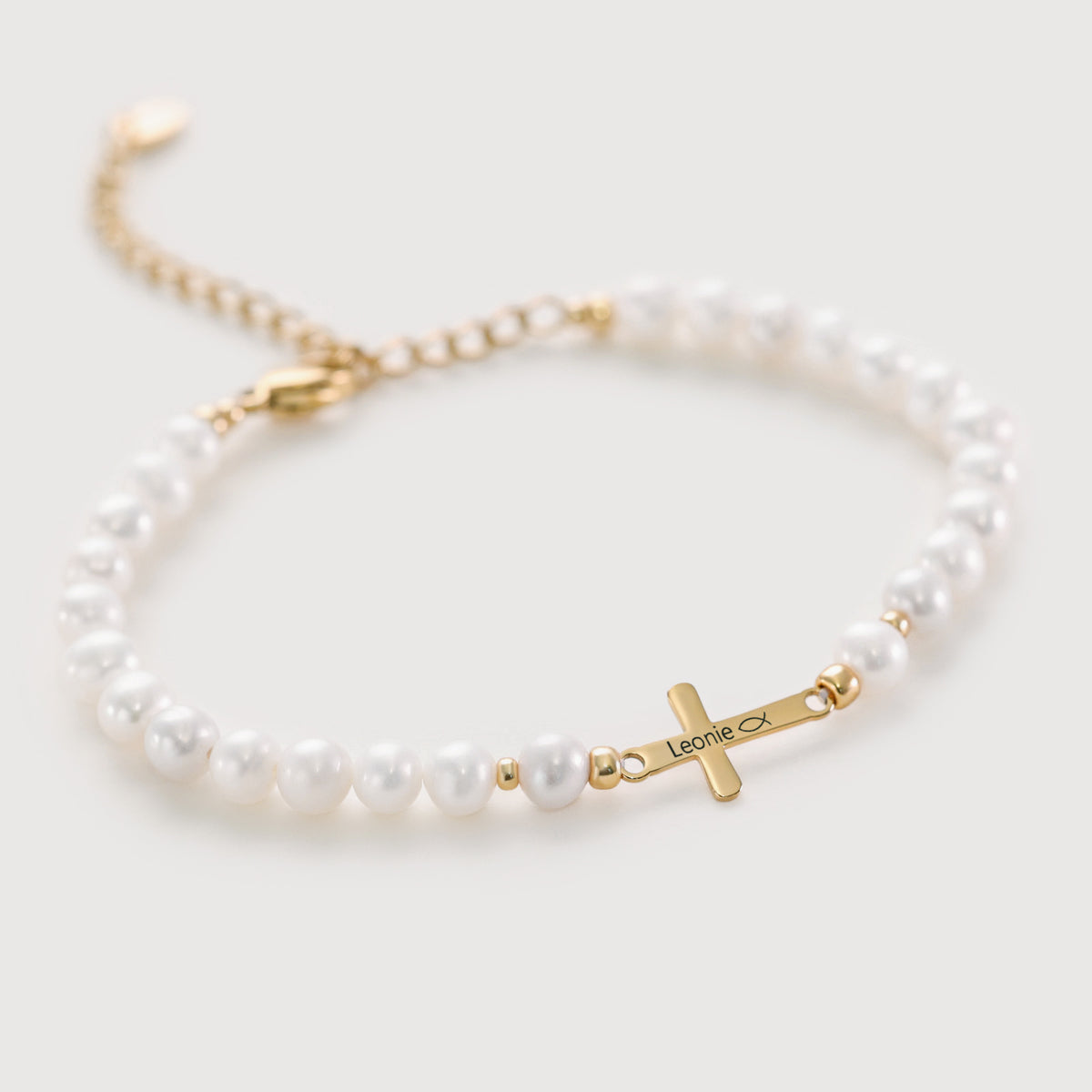 Armband mit Süßwasserperlen und Kreuz in Gold, graviert mit Namen 'Leonie' und Fisch-Symbol