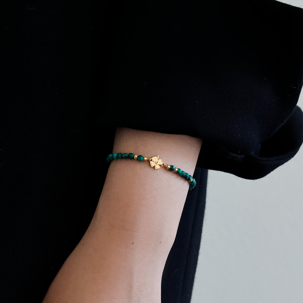 Frau trägt Malachit-Armband mit Kleeblatt in Gold am Handgelenk