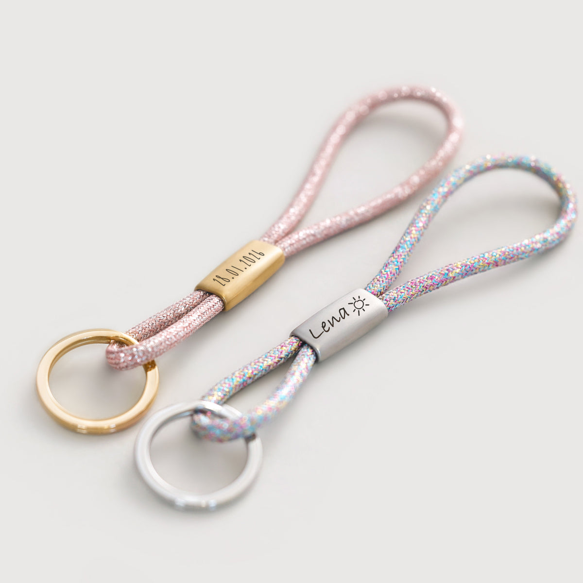 Zwei Glitzer-Schlüsselbänder in Rosé und Pastell mit Gravur 'Lena' und Sonnensymbol