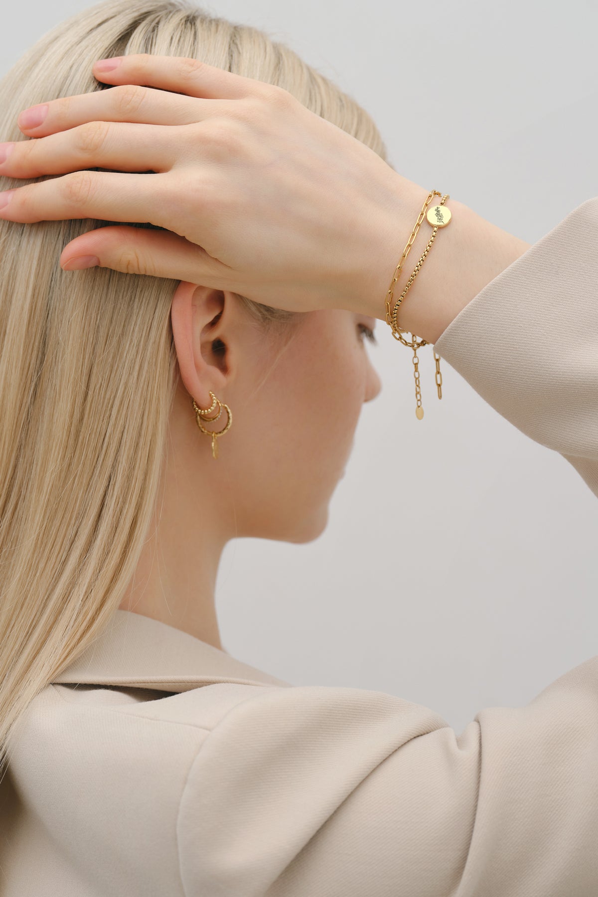 Frau trägt Geburtsblumen-Armband mit rundem Plättchen in Gold, kombiniert mit Ohrringen und Halskette