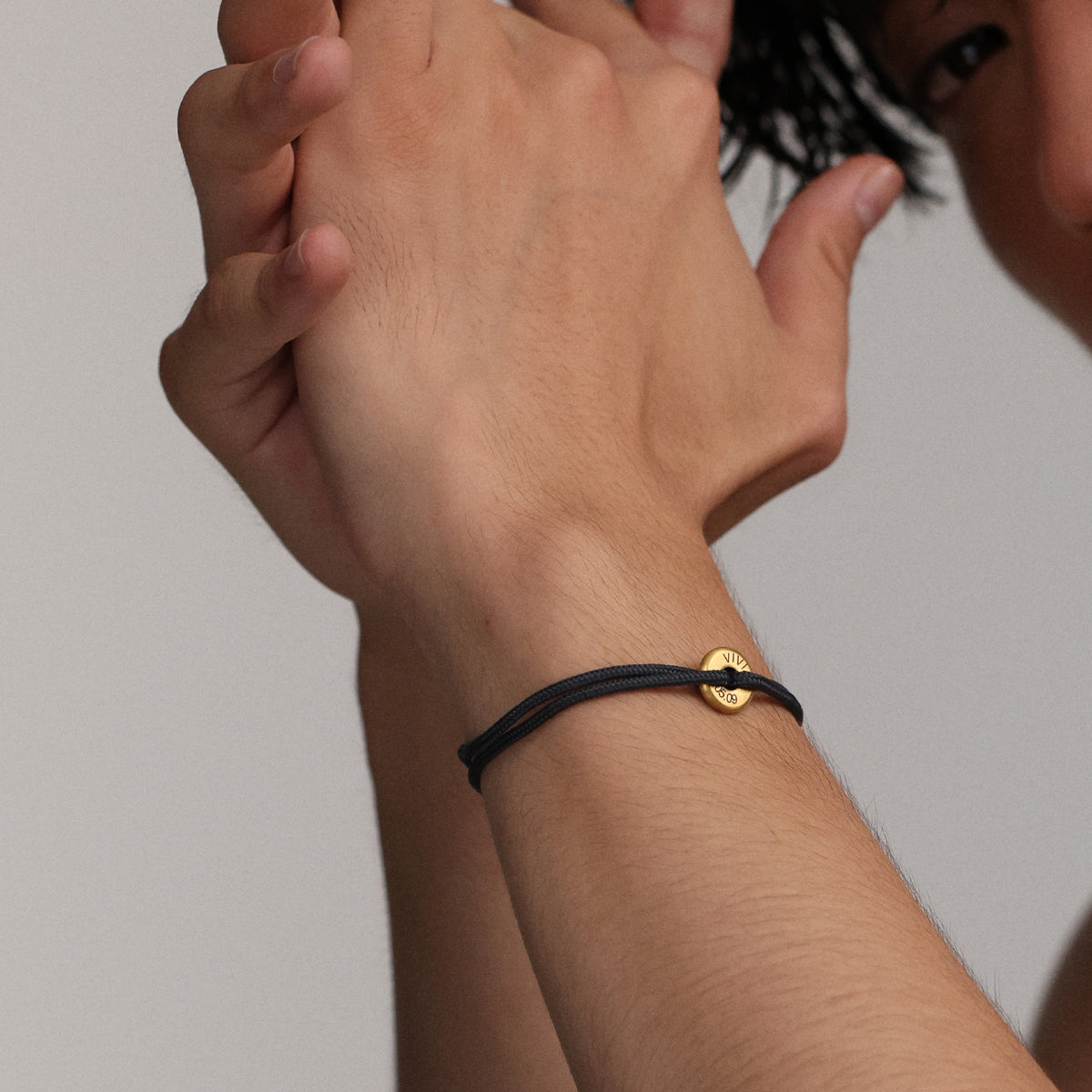 Zwei Männer halten Hände, einer trägt Segeltau Donut Armband mit goldenem Anker-Plättchen