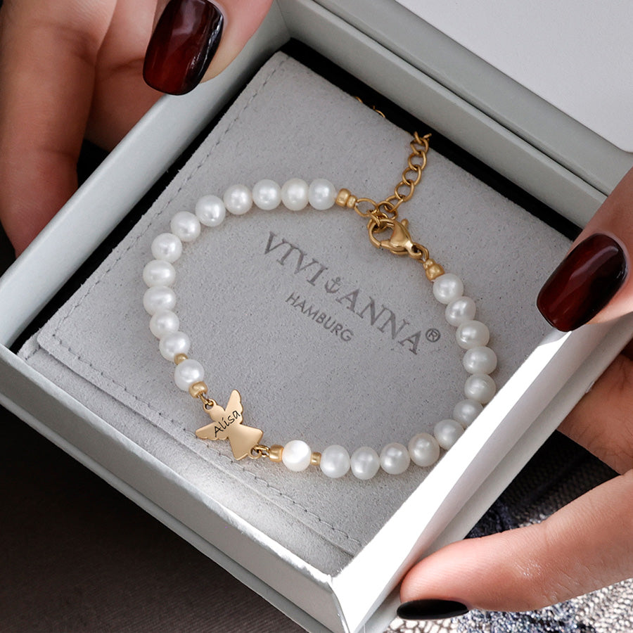 Perlenarmband mit graviertem Engel-Anhänger, in der Hand über der Geschenkbox präsentiert