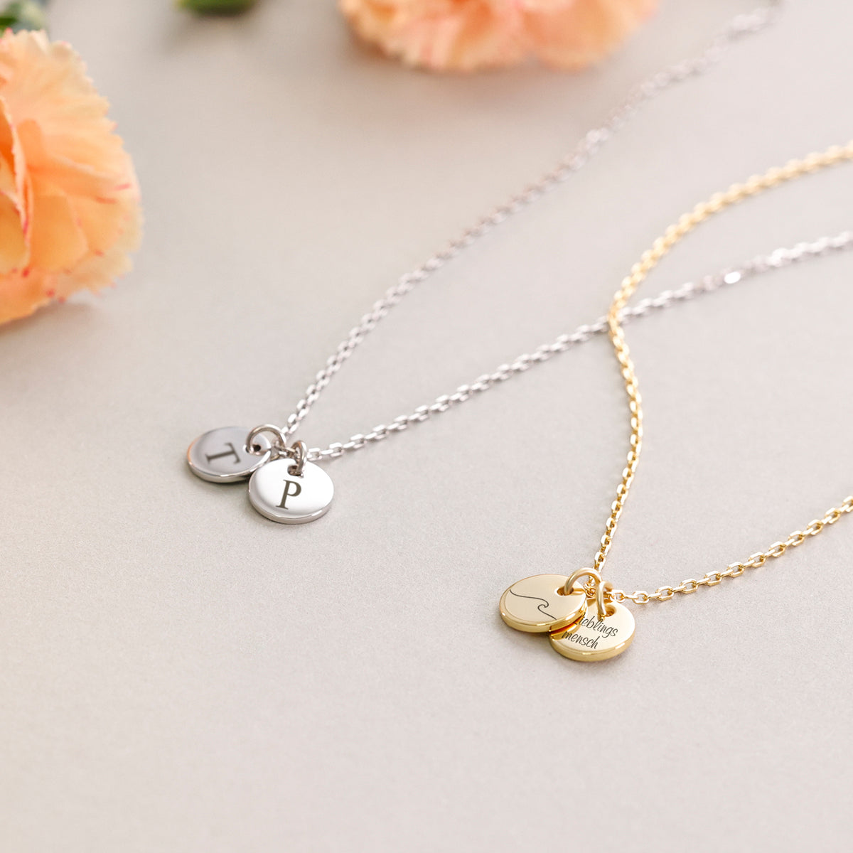 Personalisierte Kette mit rundem Plättchen – Silberkette mit Initialen und Goldkette mit Wellen-Symbol neben Blüten
