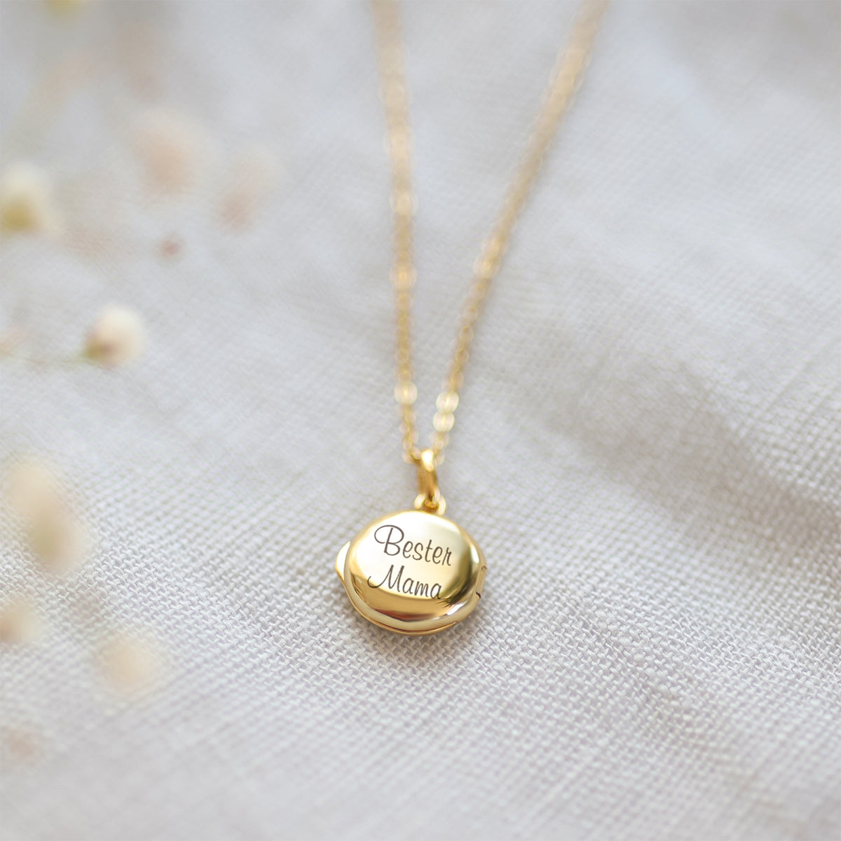 Mini Foto-Medaillon Kette mit Gravur in Gold auf hellem Leinenuntergrund