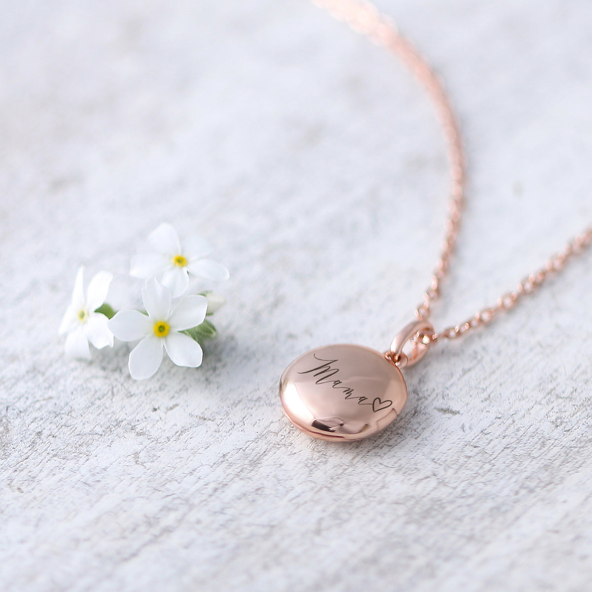Mini Foto-Medaillon Kette mit Gravur in Roségold neben Vergissmeinnicht-Blüten