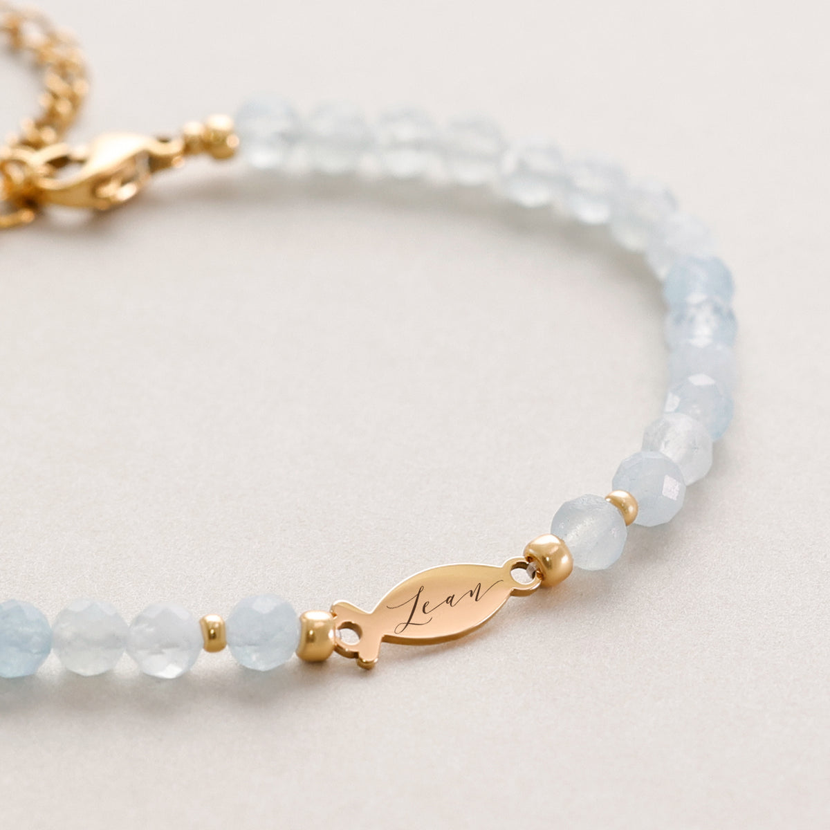 Aquamarin Ichthys Armband – Nahaufnahme des Fisch-Anhängers mit Gravur „Lean“