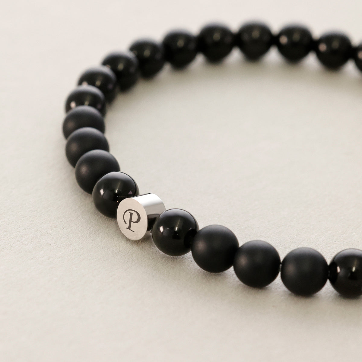 Armband mit Obsidian- und Onyx-Perlen, silbernes Plättchen mit Initiale 'P' im Detail