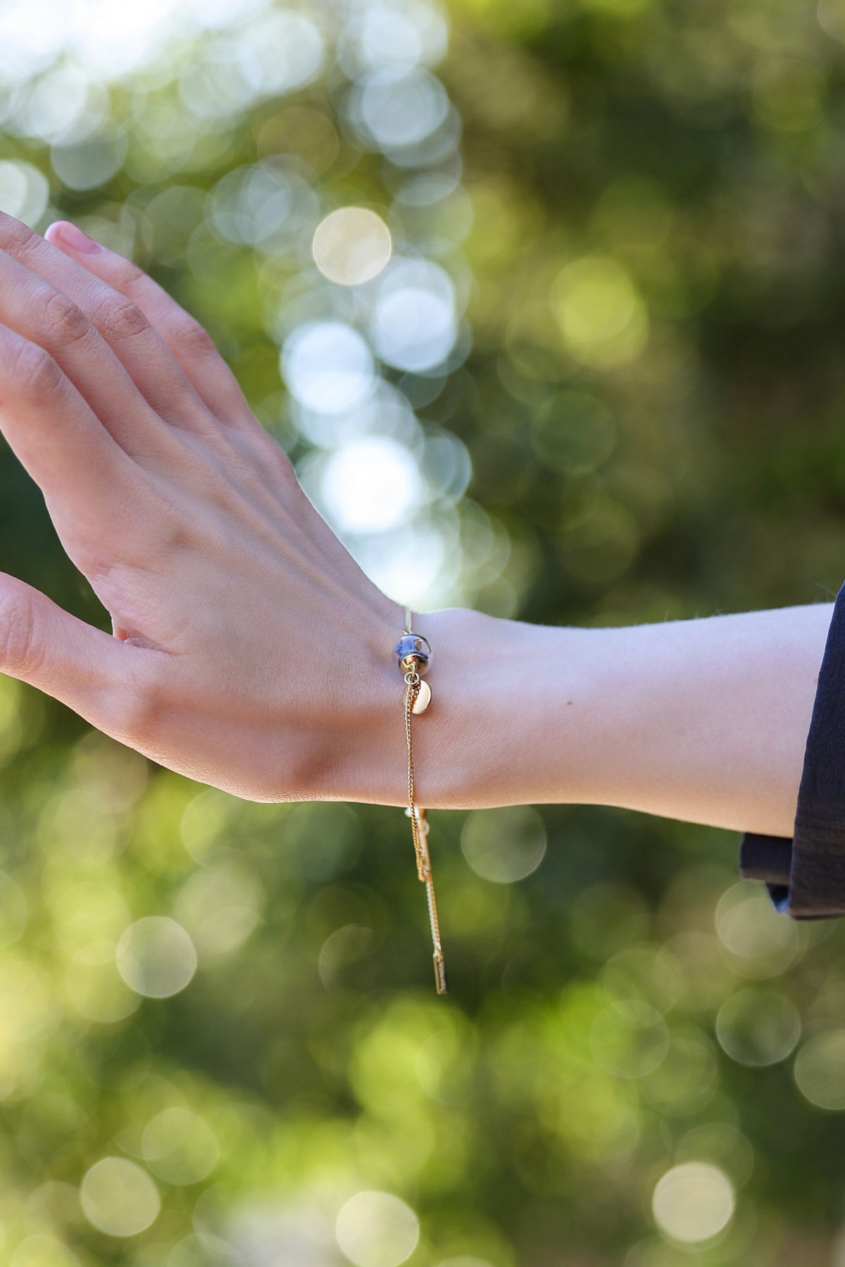 Frau trägt Vergissmeinnicht-Armband mit Gravur am Handgelenk im Freien