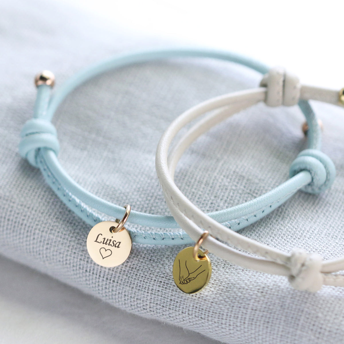 Personalisiertes Lederarmband mit Gravurplättchen – hellblaues und weißes Armband mit Namen 'Luisa' und Handmotiv