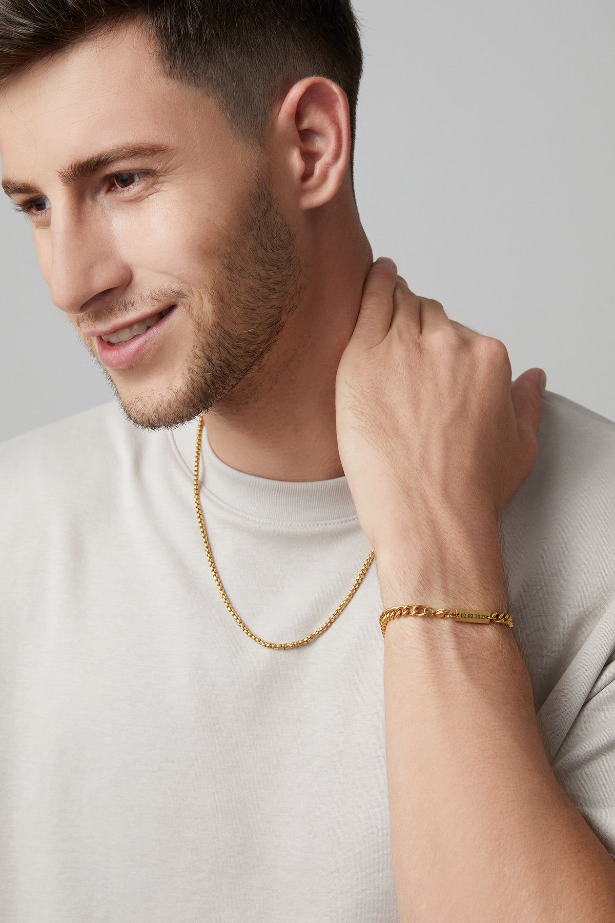 Mann trägt goldene Halskette und Panzerarmband mit Gravurplättchen, Datum '02.02.2023' graviert