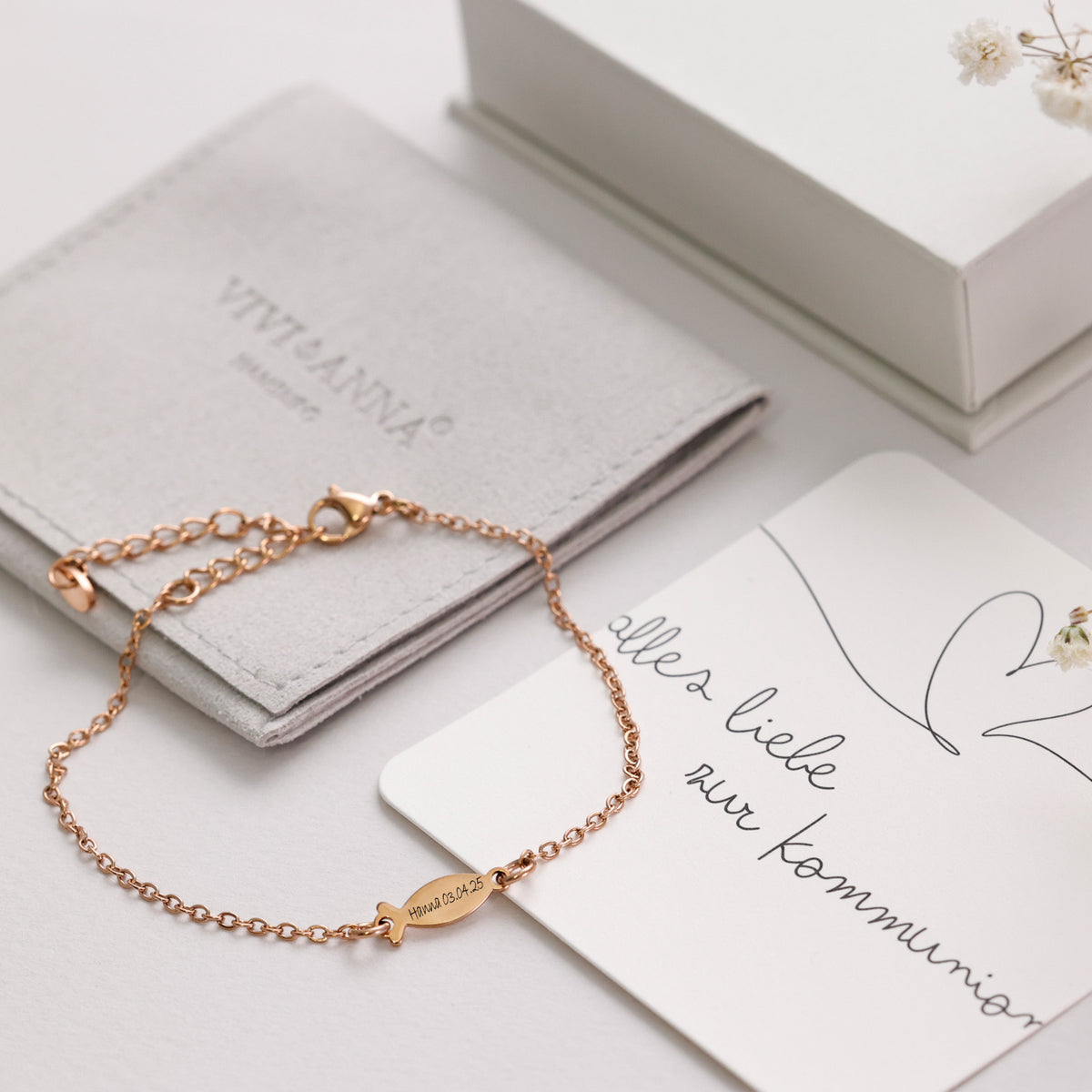 Ichthus-Armband mit Gravur in Roségold neben Kommunions-Grußkarte, Fischanhänger graviert 'Hanna' mit Datum