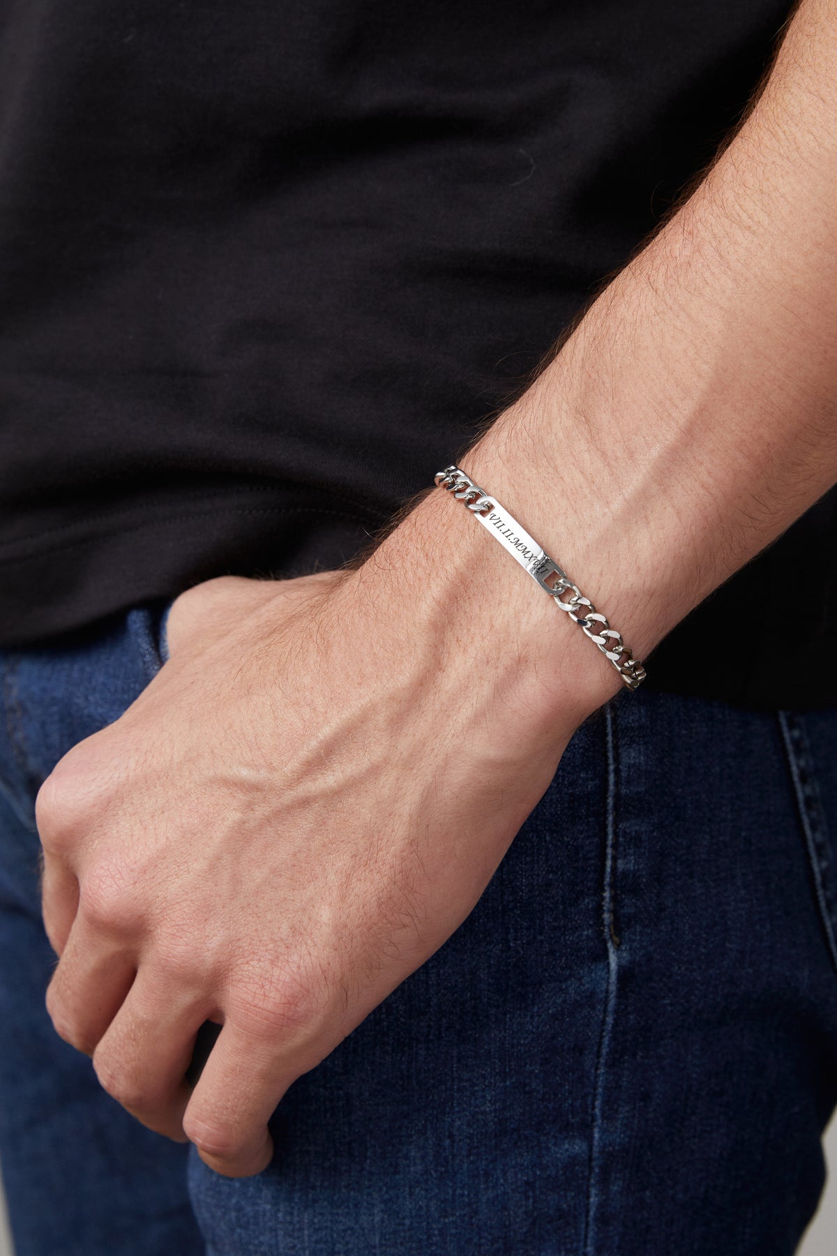 Mann trägt silbernes Panzerarmband mit gravierten römischen Zahlen