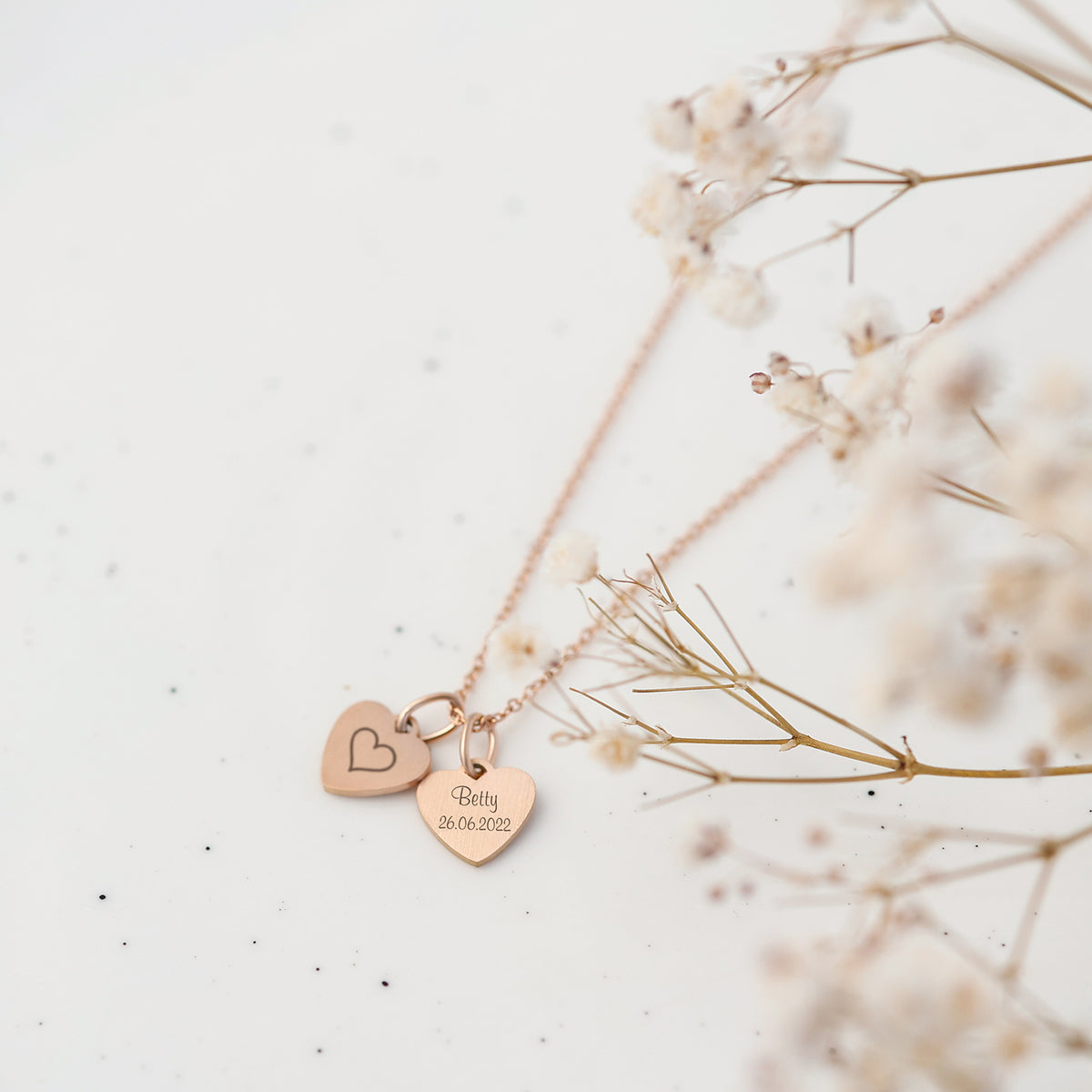 Herz Kette in Roségold mit Herzanhänger 'Mizza' und kleinen Herz-Symbolen auf Leinenstoff