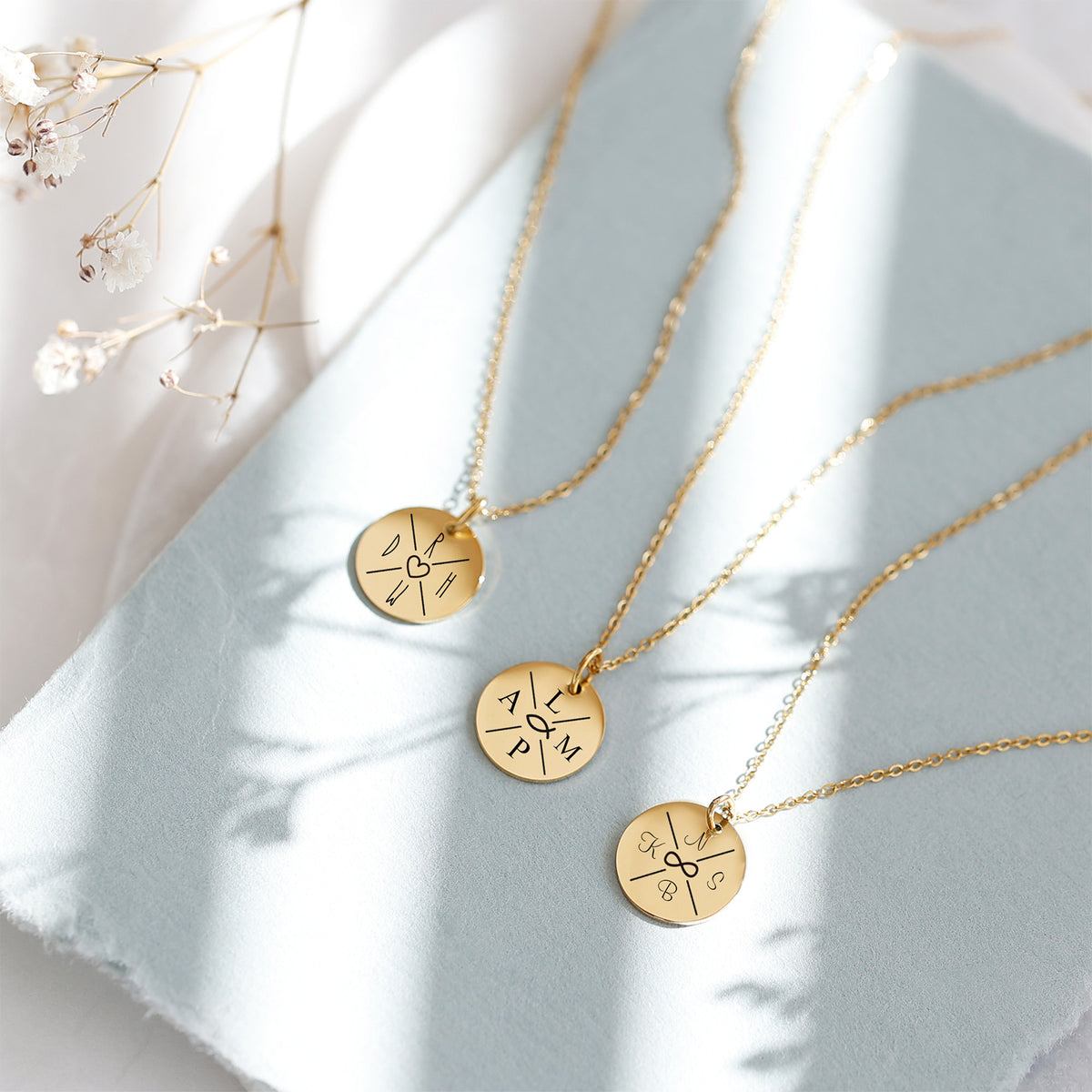 Personalisierte Familienkette mit Namen und Symbolen – drei goldene Varianten mit Initialen, Herz und Unendlichkeitszeichen