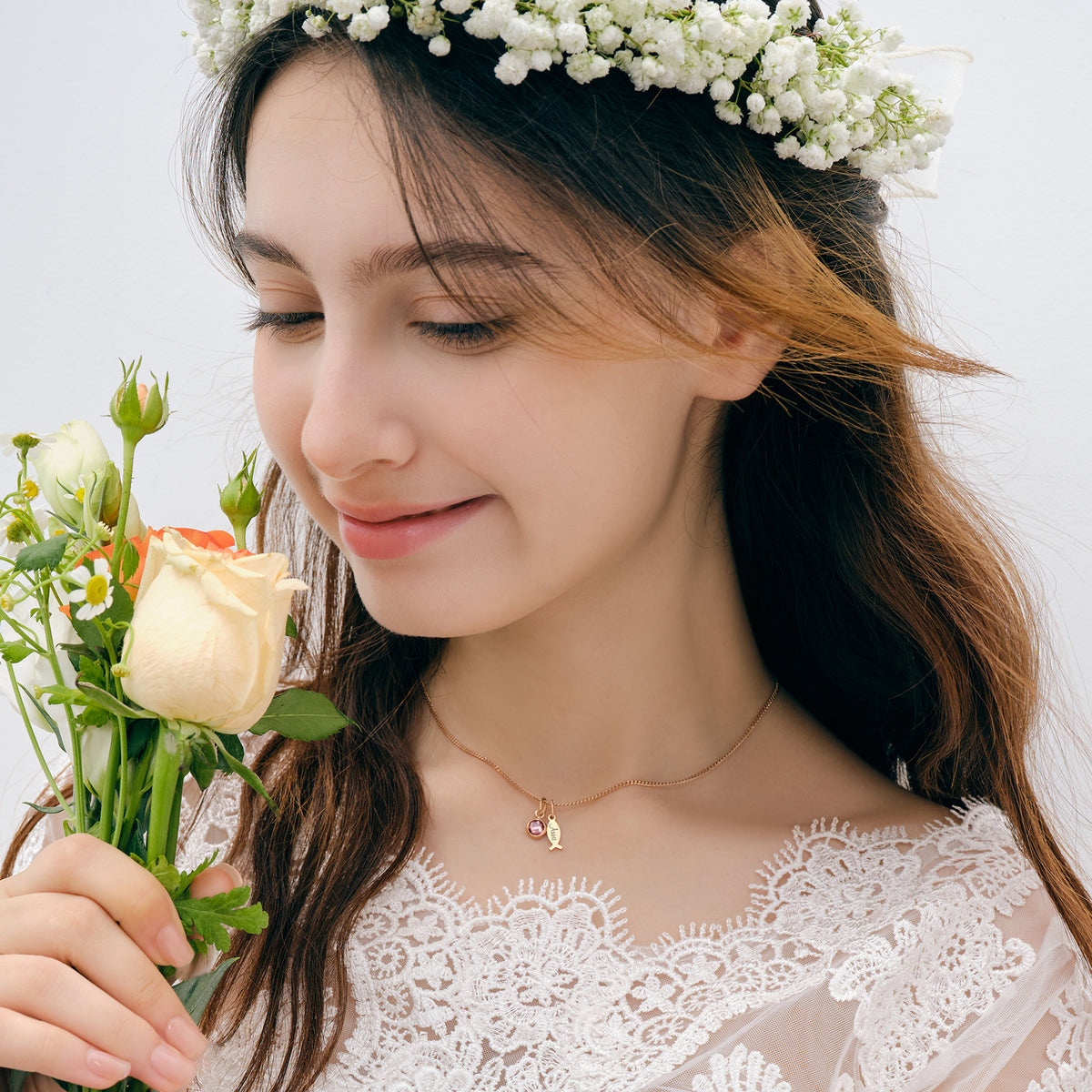 Ichthys Kette mit Geburtsstein – Mädchen mit Blumenkranz hält Rosen, goldener Fisch-Anhänger mit Stein sichtbar