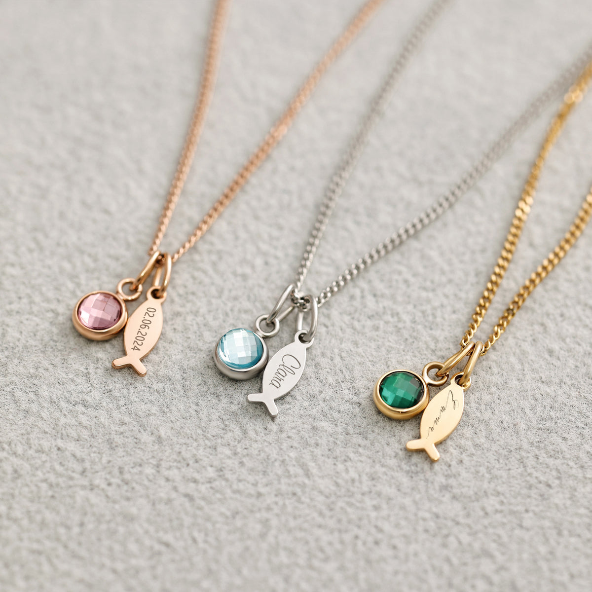 Ichthys Kette mit Geburtsstein – drei Fisch-Anhänger in Roségold, Silber und Gold mit Geburtssteinen, Flatlay