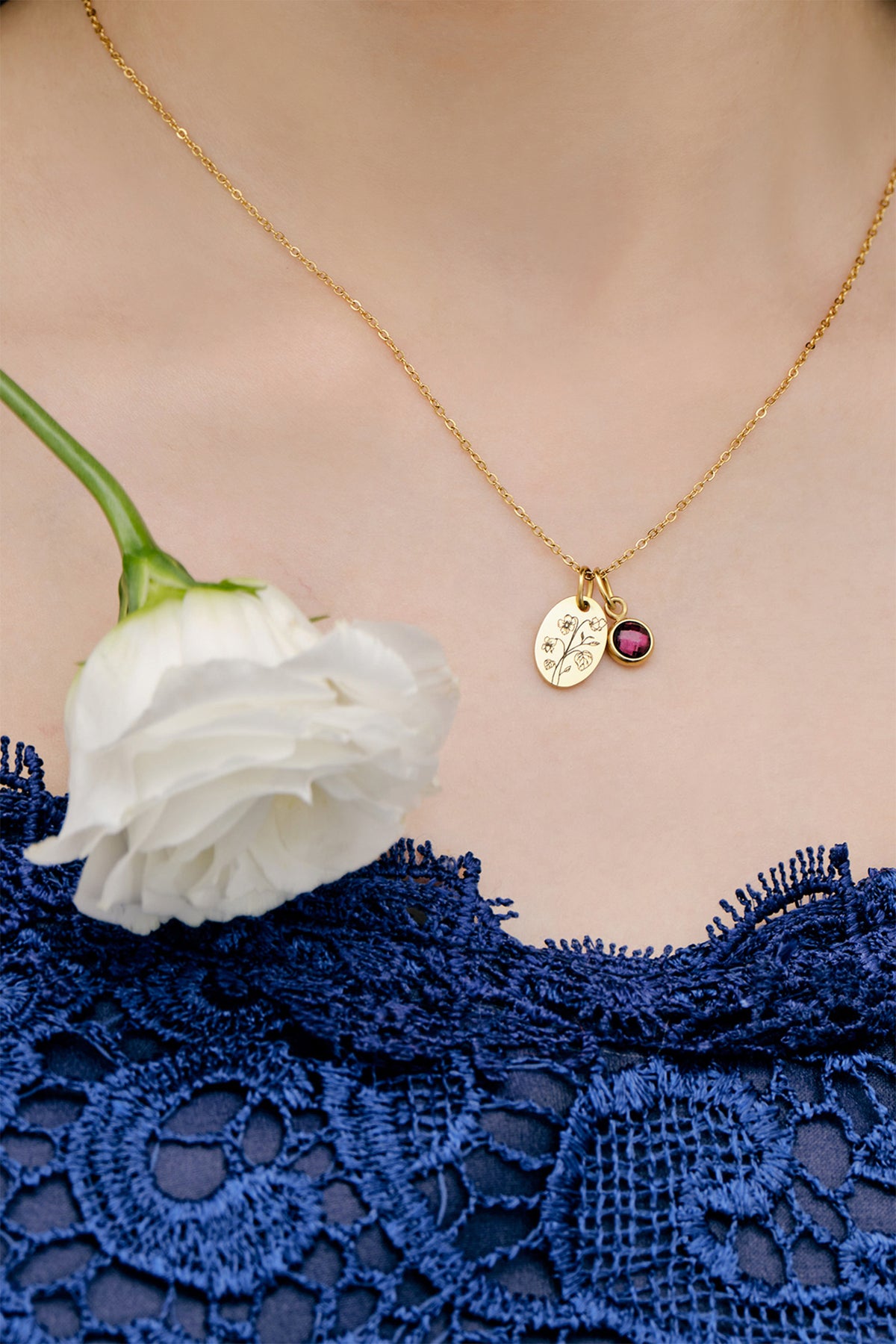 Ovales Plättchen-Kette mit Geburtsblume & Geburtsstein in Gold getragen zu blauem Spitzenkleid