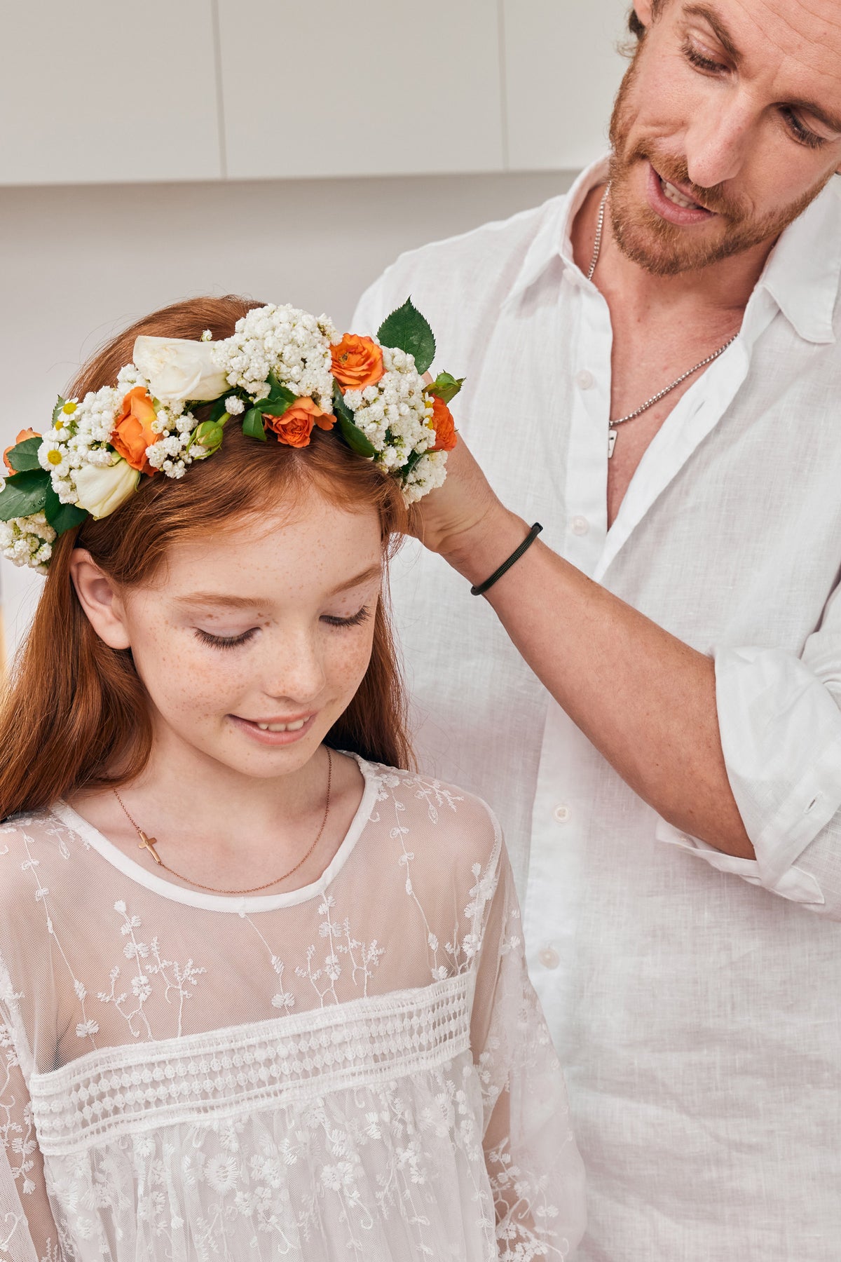 Kreuz Halskette mit Gravur – Mädchen mit Blumenkranz, Vater steckt Blumen ins Haar, goldene Kreuzkette sichtbar