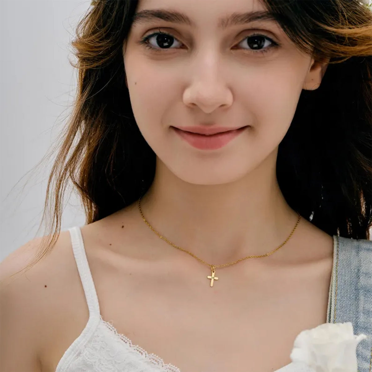 Frau trägt Mini Kreuz-Kette in Gold als zartes Collier