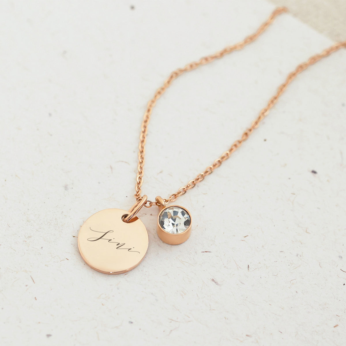 Personalisierte Kette mit Geburtsstein in Roségold, Nahaufnahme mit Namensgravur und klarem Stein
