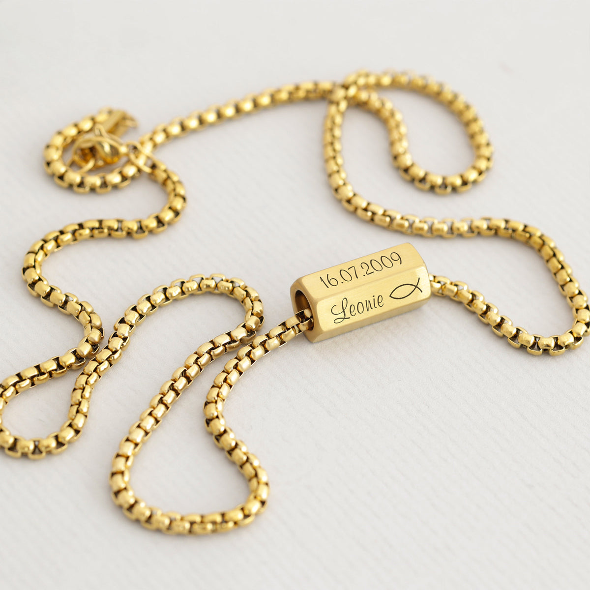 Goldene Kette mit sechsseitigem Gravurwürfel, graviert mit Datum 16.07.2009, Name Leonie und Fisch-Symbol