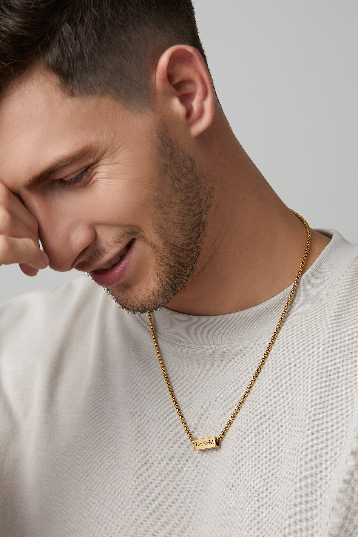 Mann trägt goldene Kette mit Gravur-Anhänger, graviert mit Initialen L & M und Herz