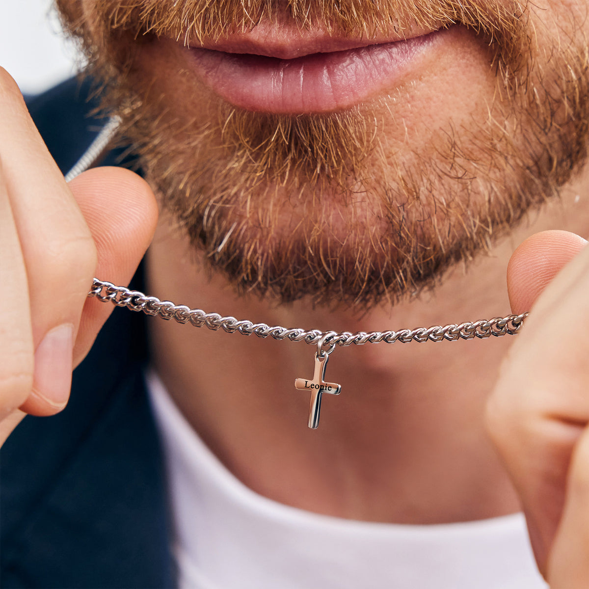 Personalisierte Herren Halskette mit Mini-Kreuzanhänger – Mann hält silberne Kette nah am Kinn, Nahaufnahme