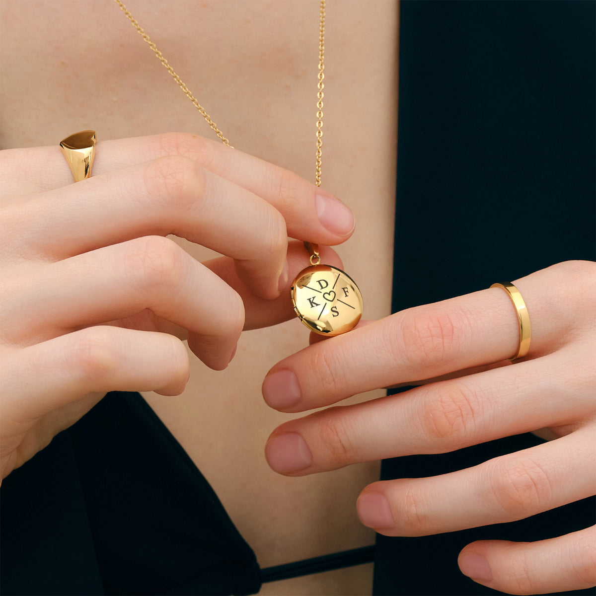 Hände halten personalisierbare Medaillonkette mit Gravur in Gold, vier Initialen und Herz