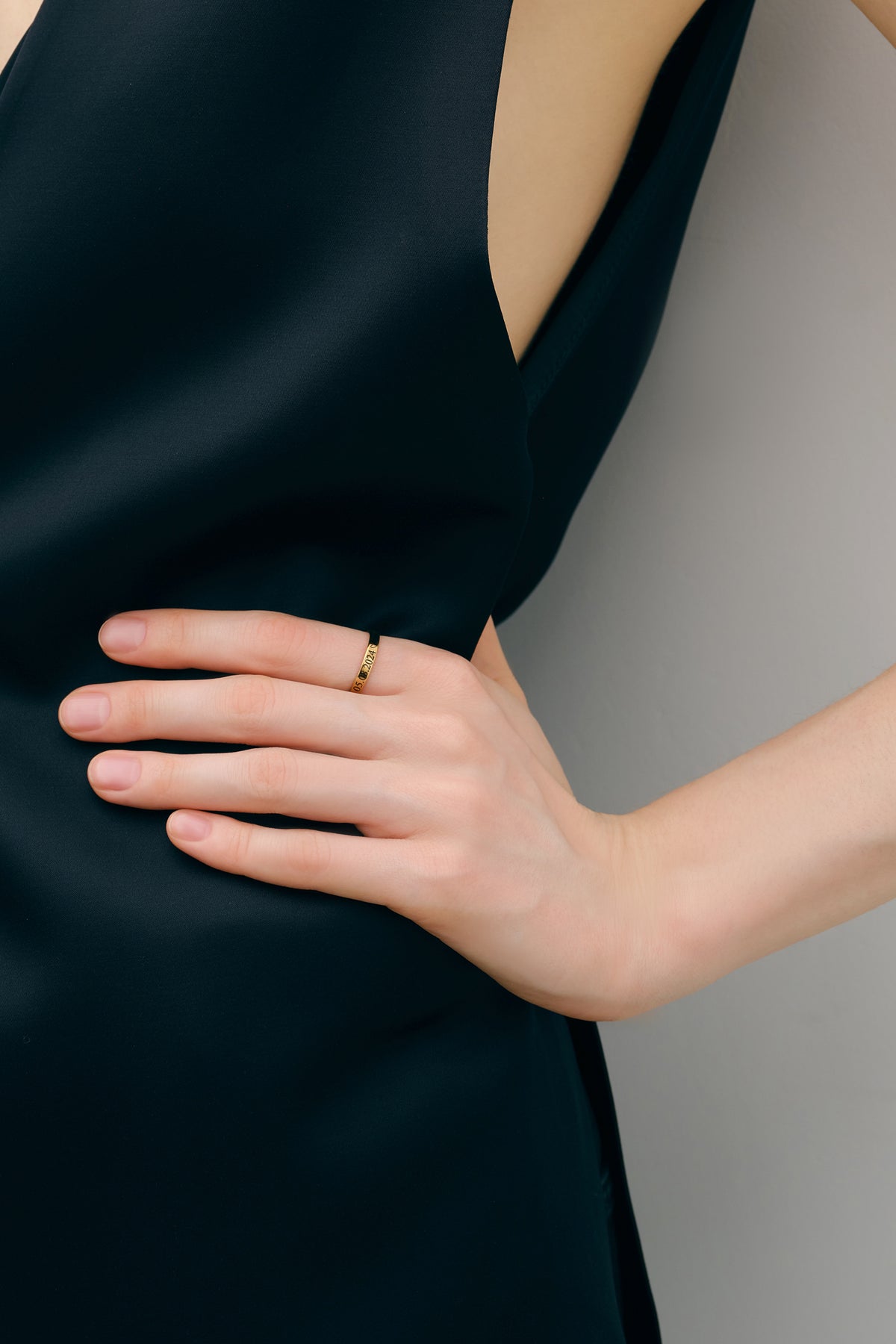 Nahaufnahme goldener Gravurring an der Hand vor schwarzem Kleid