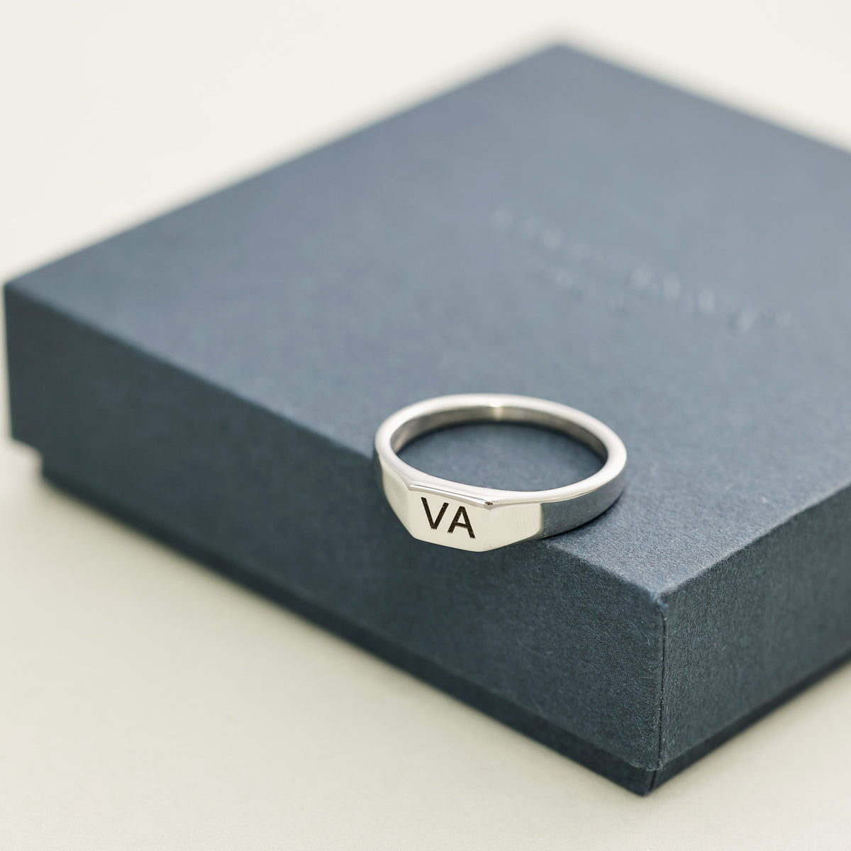 Eckiger Siegelring für Herren in Silber mit Gravur VA auf dunkelblauer Geschenkbox