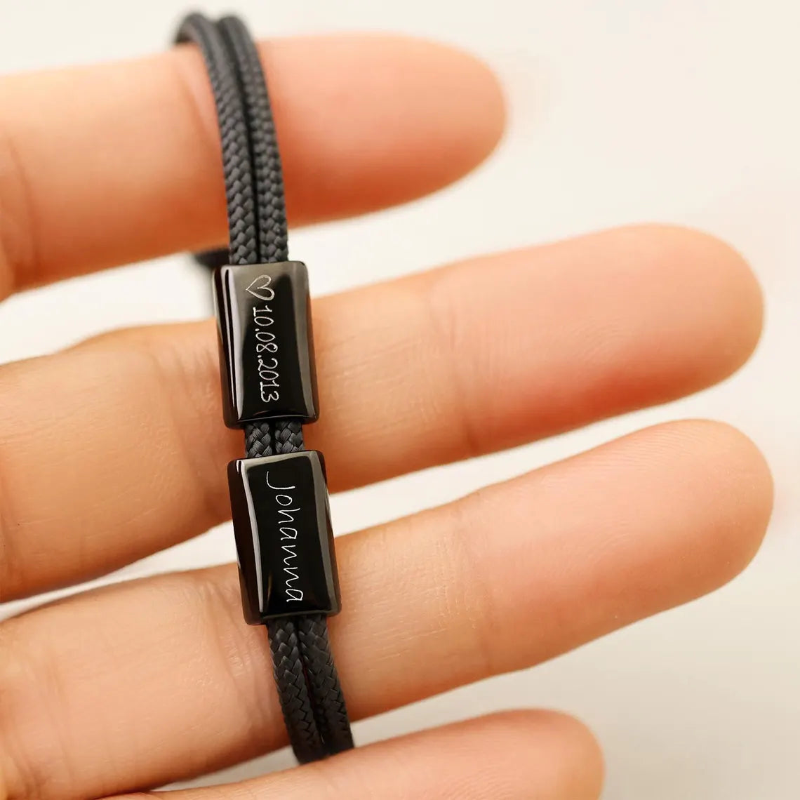 Schwarzes Segeltau Armband mit Gravurperlen am Finger – Datum 10.08.2013 und Name 'Johanna'