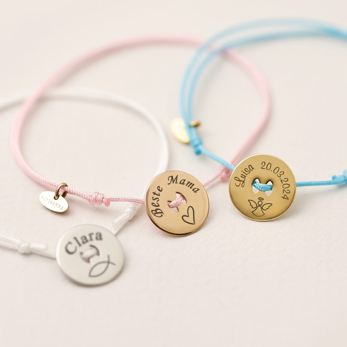Drei personalisierte Nylon Armbänder in Weiß, Rosa und Blau mit gravierten Namen und Symbolen