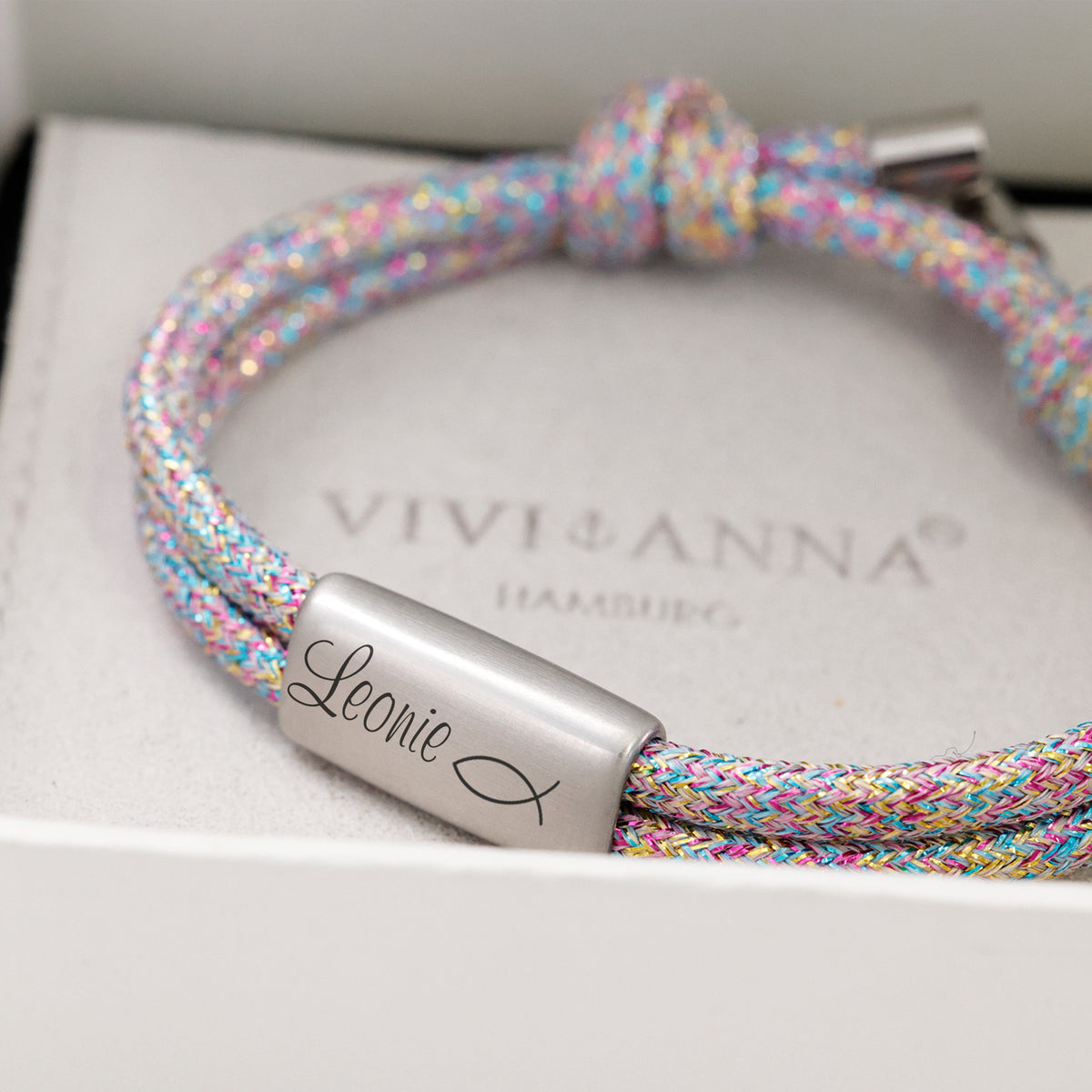 Nahaufnahme Glitzer Segeltau Armband bunt in Geschenkbox, Plättchen graviert 'Leonie' und Fischsymbol
