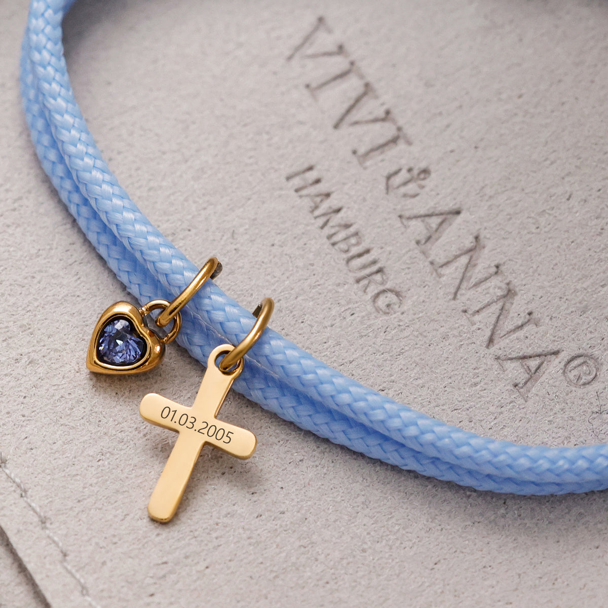 Herz-Geburtsstein-Anhänger und Kreuz mit Datumsgravur „01.03.2005“ am hellblauen Segeltau Armband