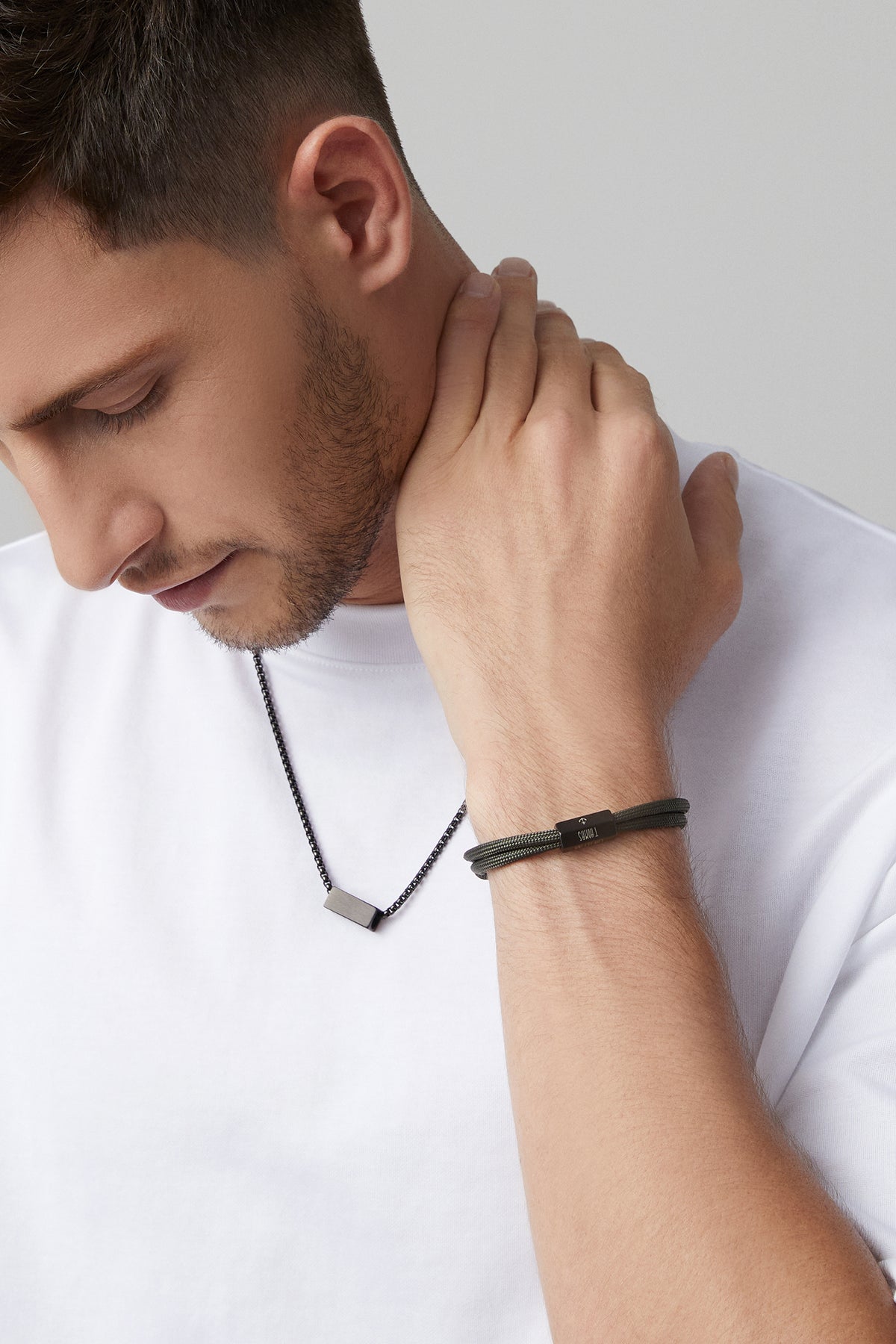 Mann trägt dunkles Herrenarmband aus Segeltau mit 6-seitiger Gravurperle und passende Halskette