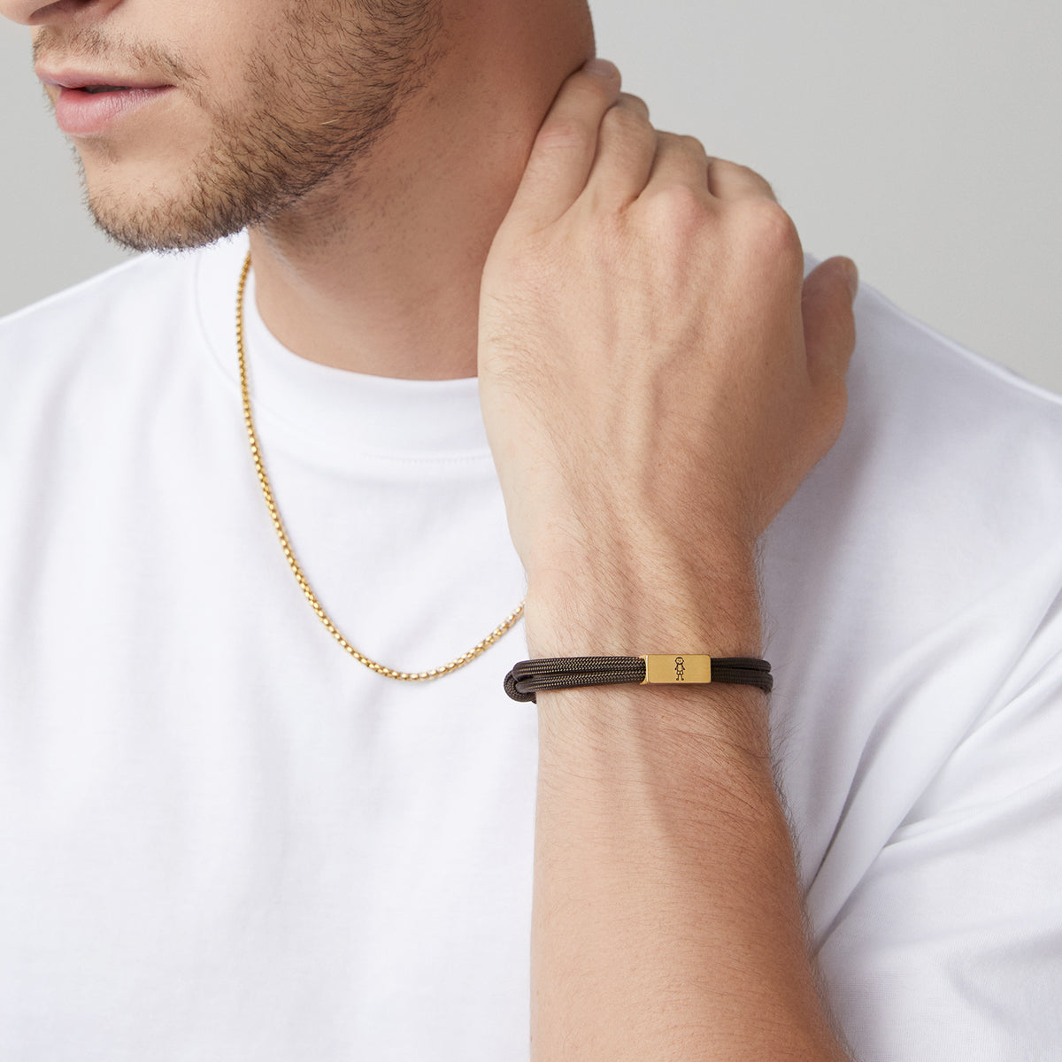 Mann trägt Halskette und braunes Segeltau-Armband mit graviertem Anhänger