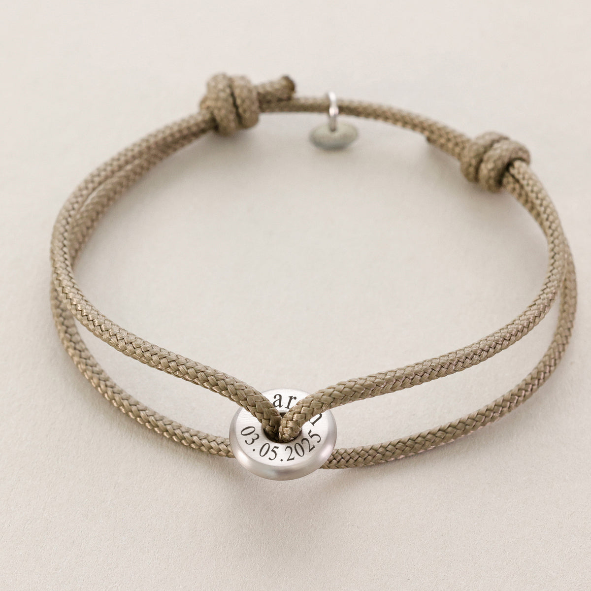 Segeltau Donut Surferarmband in Beige mit Gravur von Namen und Datum '03.05.2025'