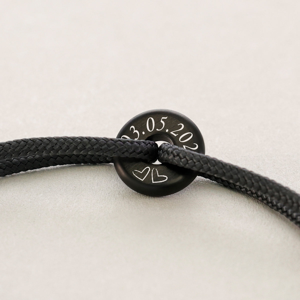 Segeltau Donut Surferarmband in Schwarz mit Gravur von Datum und zwei Herzen in Nahaufnahme